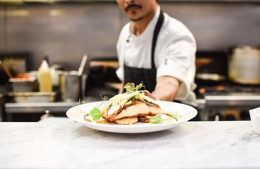 A chef finishing a plate at the pass