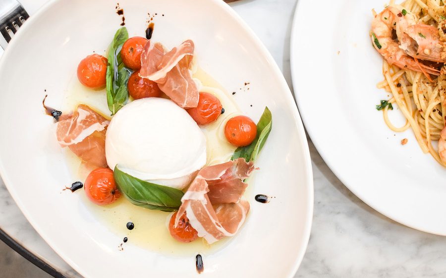 Burrata plated with prosciutto, tomato and basil